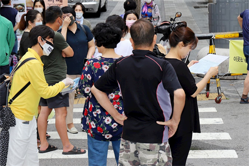 '图24:法轮功学员在韩国首尔街上派发简介,让市民了解真相。'