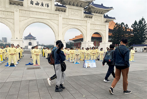 '图1~2:被疫情笼罩的台北市,法轮功学员集体炼功散发的祥和能量场吸引前来自由广场的游客驻足拍照,拍下这珍贵的场面。'