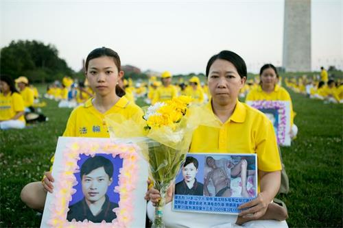 '图5:二零二一年七月十六日晚,一千多名法轮功学员在美国首都华盛顿DC举办烛光悼念。图为迟丽华(右)和女儿徐鑫洋手捧丈夫徐大为的遗像。'