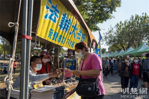 '图3:路竹番茄节设有法轮功展位,不断有民众前来拿取法轮功资料和写有九字真言“法轮大法好 真善忍好”的小莲花饰品。'
