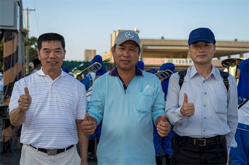 '图6:兴达港观光渔市总干事郑先生(中),热情邀请法轮功学员来兴达港观光渔市炼功弘法。看到好多民众跟随天国乐团涌入,总干事和来宾为法轮功比赞。'