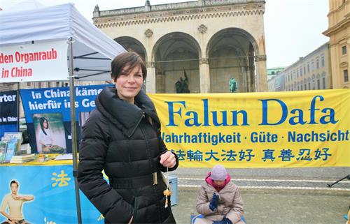 '图3:专利律师事务所办公室经理普利兹芮尼(Anja Prizreni),手拿带有真、善、忍字样的小莲花很开心。'