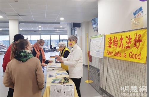 '图2:弗蕾德里克(身着白色上衣者)向学校师生们介绍法轮大法真相,传播法轮大法的美好。'