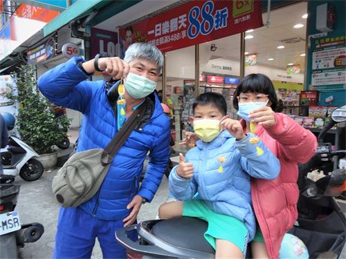 '图9:法轮大法学员在游行途中派发小莲花吊饰,民众拿到后非常开心。'