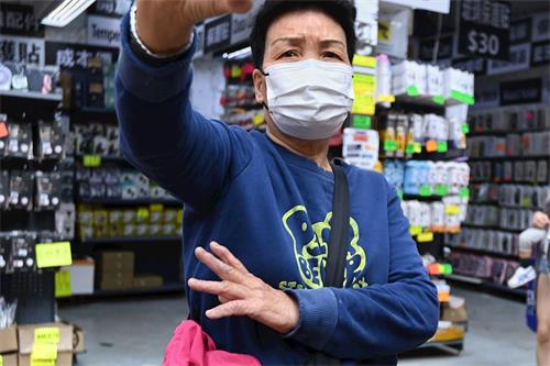 '图1~2:在香港旺角到处放置诬蔑法轮功展示架的老妇,被发现后自曝听命于深圳共产党。'