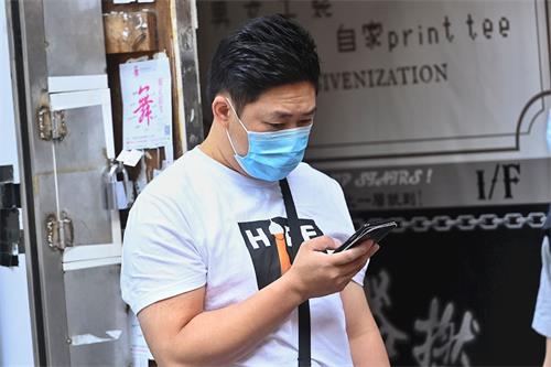 '图3:自称是摆放展示架老妇的儿子,全程在为老妇以手机拍照。'