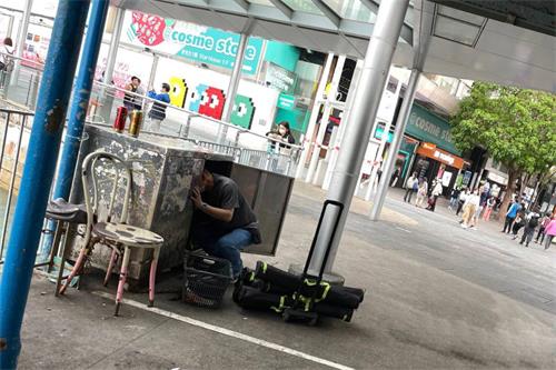 '图4:尖沙咀负责摆放展示架的男子,到青关会的铁柜里面,取出诬蔑法轮功的展示架,显示该团体和青关会关系密切。'
