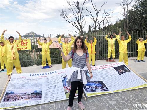 图7:希腊女士手持带有“真善忍”书签的小莲花