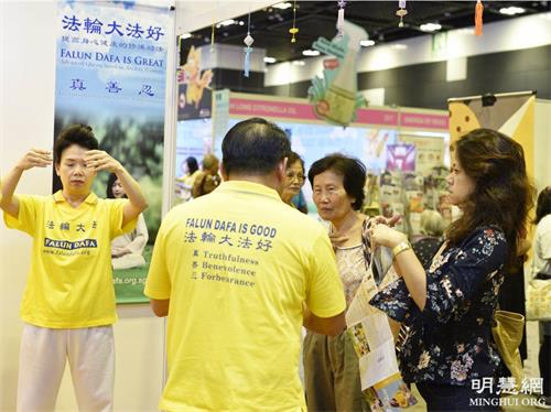 '图4:二零一九年五月,在新达城的健康保健展上,乔迪(Jodi,右,穿深色花上衣的女士)在法轮功的展位旁了解真相。'