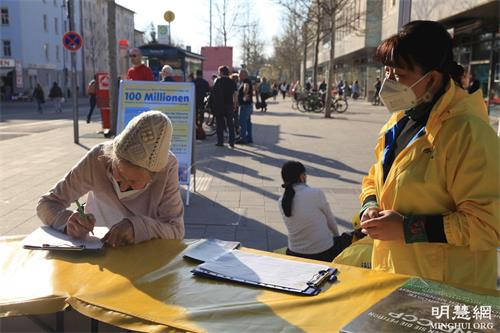 '图5:一位民众非常仔细的阅读签名表之后,郑重签名。'