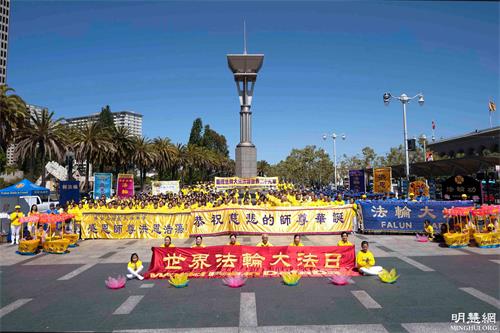 '图22:游行出发前,法轮功学员集体合影,恭敬合十,恭贺师父华诞,齐声念颂:“恭祝师父生日快乐!”“法轮大法好!”“真善忍好!”表达法轮功学员对师父的崇敬和感恩。'