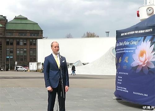 '图11:伊尔马里通过麦克风介绍法轮大法洪传世界。'