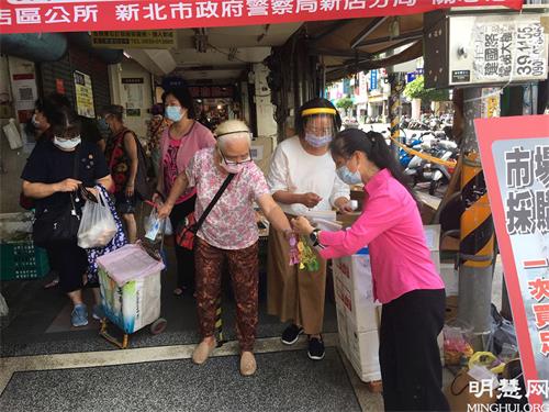'图1~2:法轮功学员在市场门口为民众量体温并借机传递真相资料和小莲花'