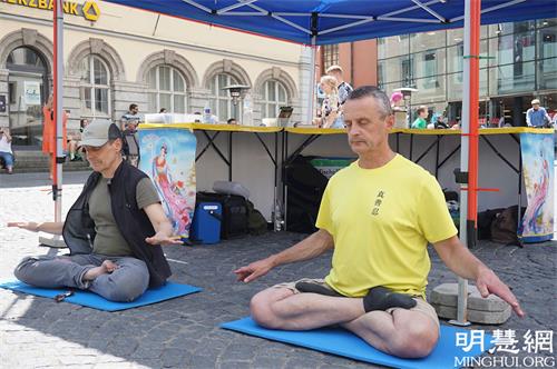'图2:法轮功学员在四管喷泉旁的真相展位打坐'