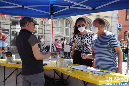 '图3~5:在四管喷泉旁的展位上,民众和法轮功学员交谈了解真相,并签名支持法轮功'
