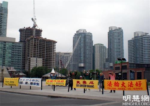 图2:每天一早,86岁的法轮功学员黄韵琴就到电视塔前挂横幅,一挂就一大排,迎接中国游客。