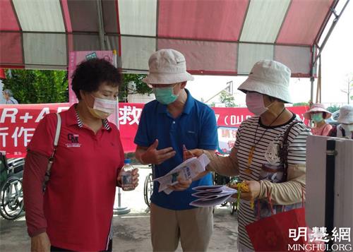 '图1~2:在嘉义县民雄国中疫苗施打站,法轮功学员派发特刊,告诉人们诚念九字真言会带来平安福报。'