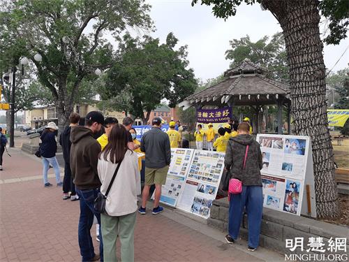 '图2:集会现场吸引很多民众驻足观看真相展板'