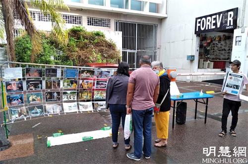 '图12:留尼汪岛法轮功学员在展位前讲真相'