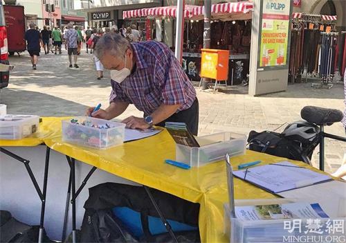 '图2~3:了解真相的民众在请愿书上签名,支持法轮功学员反迫害。'