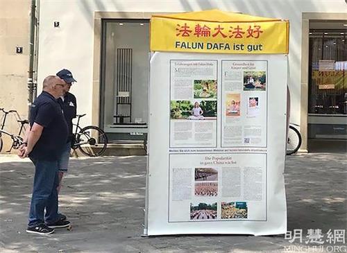 '图4:这两位男士正在认真阅读真相展板。'