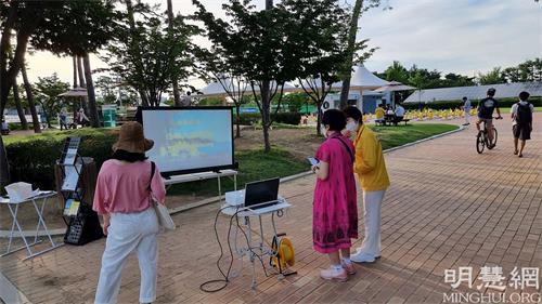 '图6~7:大邱市民观看法轮功学员展示的真相看板与法轮功介绍视频。'