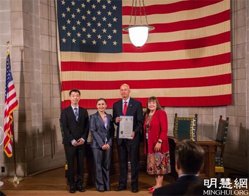 图2:2021年6月24日,美国内布拉斯加州州长皮特·里基茨(Pete Ricketts)在州议会大厦宣布7月为“共产主义受害者纪念月”。右二:州长。左一:法轮功学员王先生。