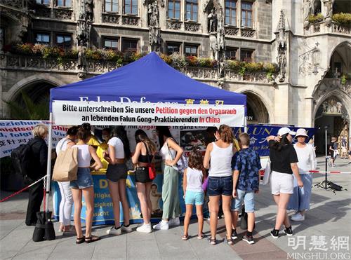 '图1:二零二一年八月十日,德国法轮功学员在慕尼黑玛琳广场(Marienplatz)举办活动。图为民众排队签名声援法轮功学员反迫害。'