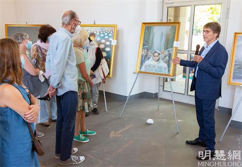 '图1:二零二一年八月十二日到十八日,“真善忍国际美展”在德国北部重镇杜赛尔多夫市北方公园(Nordpark)展览厅举行,图为一位法轮功学员(右一)为美展的参观者导览。一位讲解员有时会同时为近二十位参观者讲解。'