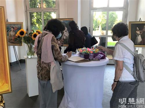 '图2:一位参观者在美展留言簿上留言。'