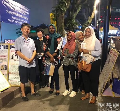 '图5~6:游客明白真相,与法轮功学员合照,表达了对法轮大法的支持。'