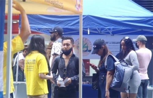 '图8:来自法国的华人留学生杨德雄在听法轮功学员讲述真相。'