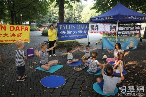 '图5:二零二一年八月二十一日,法轮功学员在慕尼黑的霍亨索伦广场(Hohenzollernplatz)举办活动。一群小朋友和一位德国妇女带着孩子一起跟学员学炼打坐。'