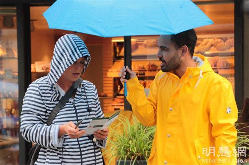 '图4:路人在雨中了解法轮功真相'