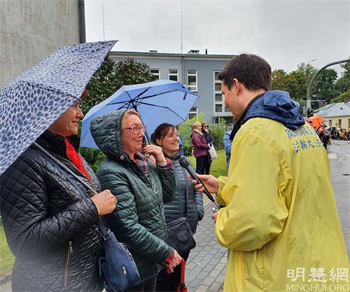 '图11:观众约兰特(Jolant,左二)女士注意到舞龙者身上的T恤衫都写着真、善、忍字样,她说:“我觉得太好了,这是我们在现实生活中丢失很久的美好信仰,需要恢复出来,世界需要真、善、忍”。'