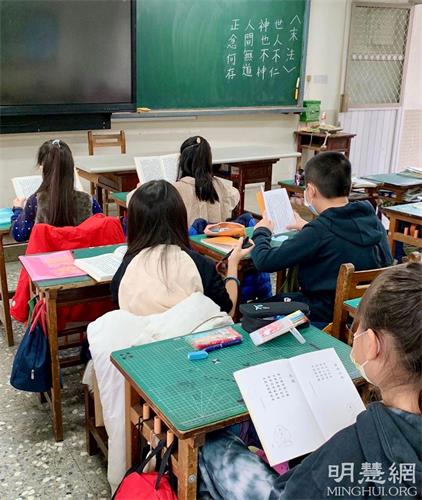 '图1:孩子认真念读并抄写《洪吟》。'