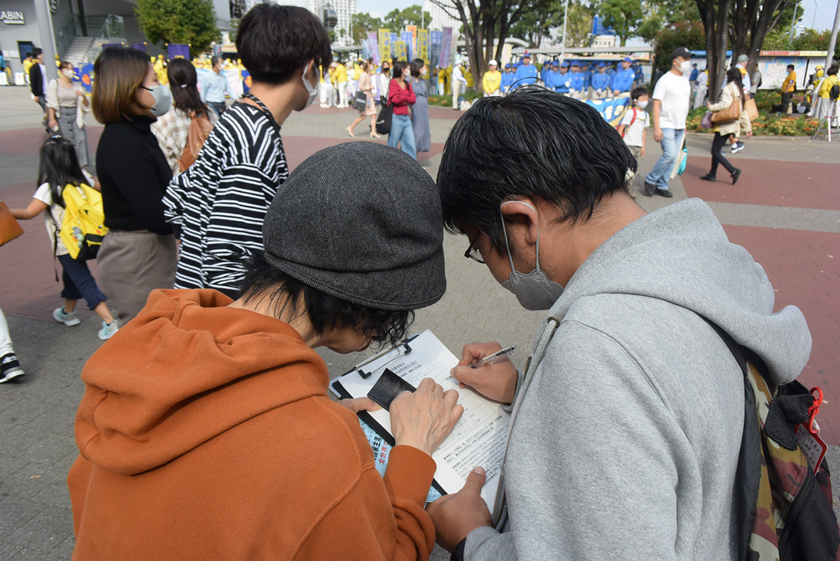 图20:正在签名支持法轮功反迫害的小杉先生(右)