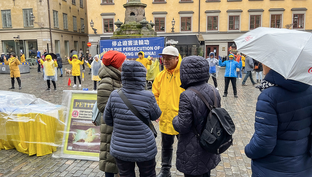 图1:金秋十月,时雨时晴。法轮功学员冒雨在诺贝尔博物馆前举办讲真相活动,学员们展示功法,民众主动上前了解真相。