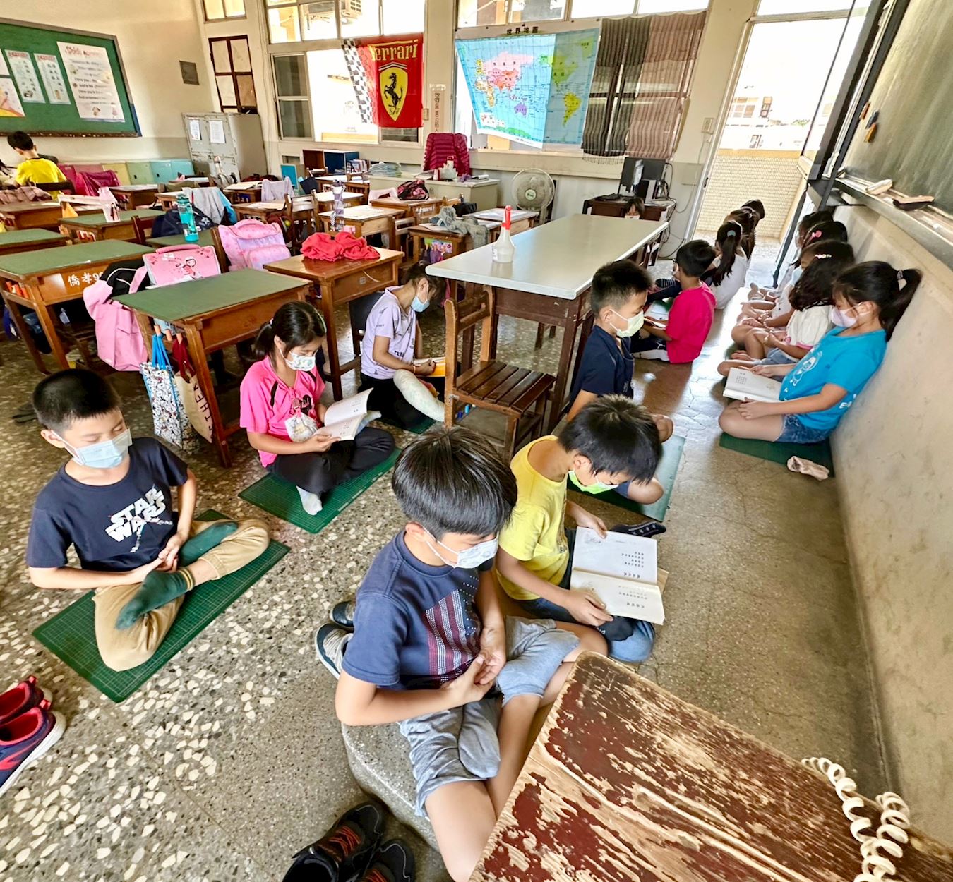 '图2:午休时王郁青的学生恭读《转法轮》《洪吟》,一旁的学生打坐。'