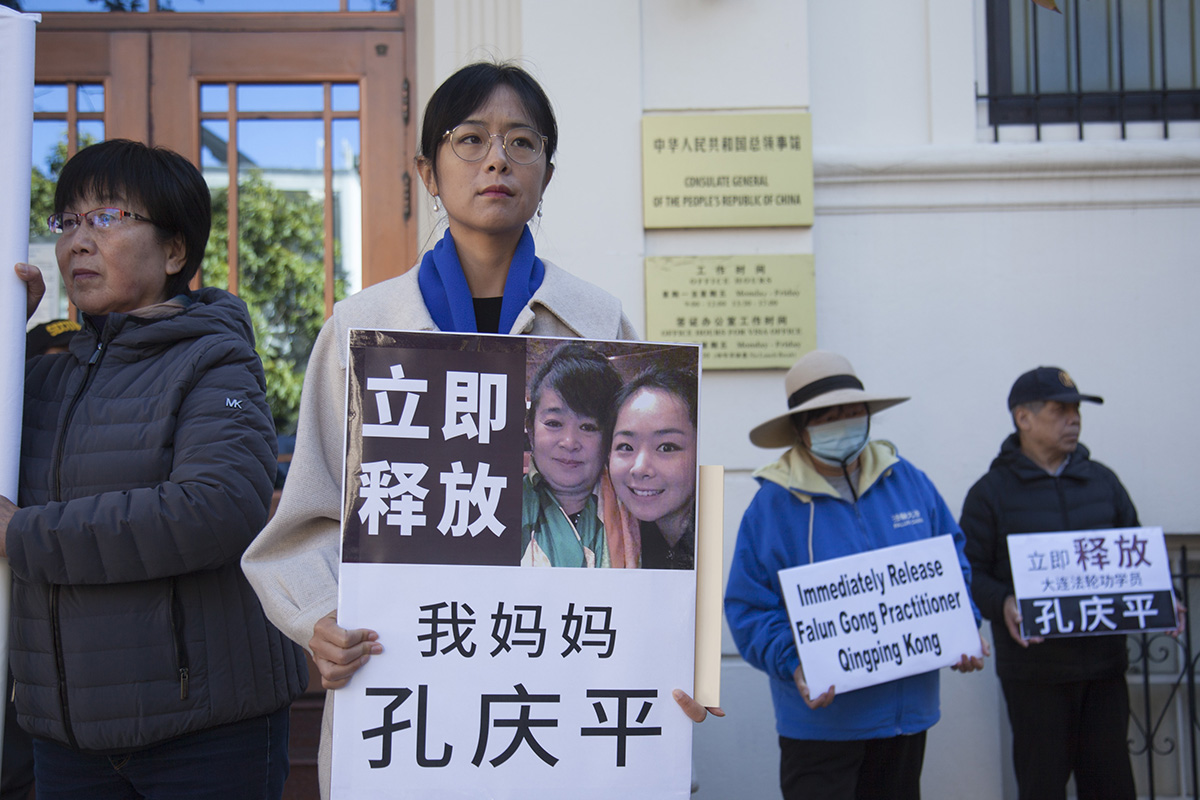 湾区居民刘芷彤在中共旧金山总领馆前,展示与母亲孔庆平的照片,要求中共当局立即释放自己的母亲。