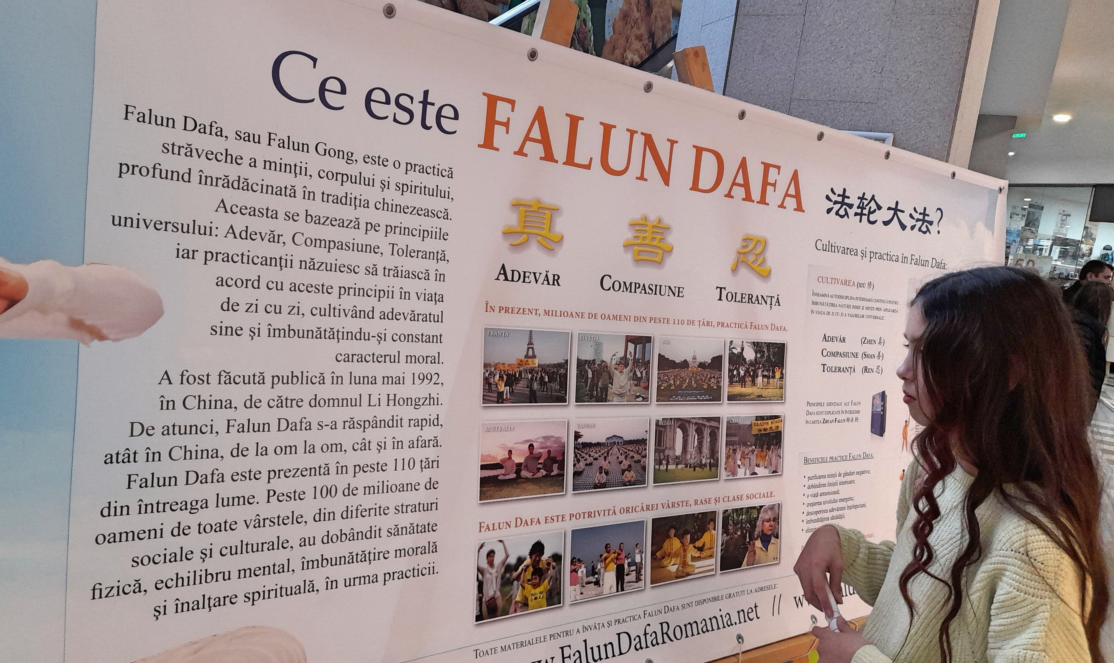 图3:尤利亚认真阅读真相展板。她询问在哪里有炼功,然后耐心而愉快地听学员介绍什么是大法。