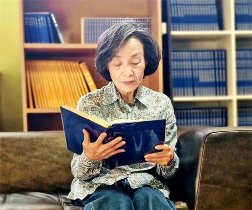 '图2:曾经因为视力模糊而无法看字的李英兰女士现在每天沉浸在读《转法轮》的快乐中。'