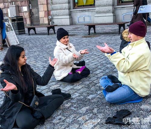 '图2:前来了解真相的人们,有人对功法感兴趣当场就学炼法轮功。'