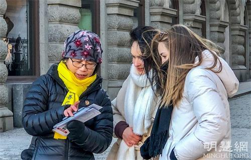'图5:两位来自德国年轻的姑娘顶着寒风很专注地在听学员讲真相。签名让她们感到很荣幸,她们认为“迫害很可怕,但沉默比迫害更恐怖!”'