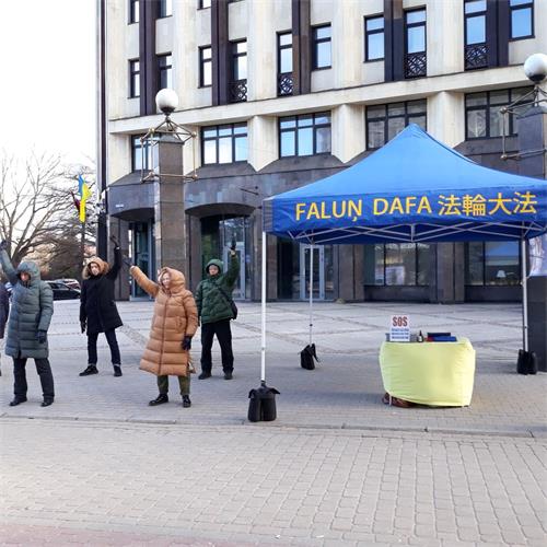 '图2:法轮功学员在老城市中心搭起真相展位并展示功法'