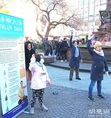 '图4:父亲在签名支持的时候,女儿在模仿法轮功学员的炼功动作