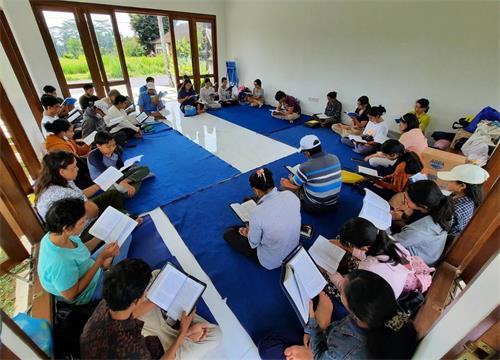 图2:在乌布皇宫周边的活动结束后,青年法轮功学员们与他们的父母亲们,在德格拉朗一起阅读《转法轮》。