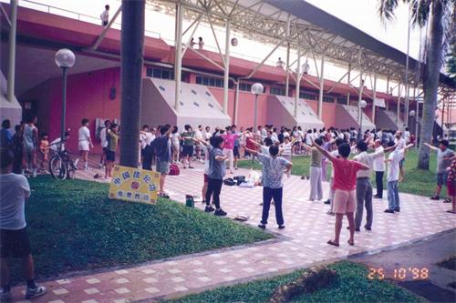 '图11:自一九九五年起,法轮大法在海外洪传,新加坡全岛各地陆续成立了炼功点。很多当年的老学员就是在炼功点上入道得法的。图为一九九八年学员们在金文泰体育场炼功点集体炼功。'