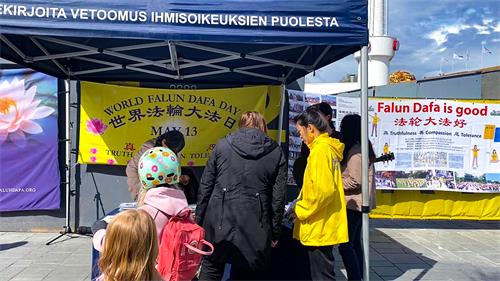 图2:在赫尔辛基闹市区,人们驻足“法轮大法日”庆祝活动真相展位