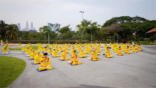 '图2~3:马来西亚部份法轮功学员在吉隆坡著名的休闲公园——蒂蒂旺沙湖滨公园(Titiwangsa Lake Garden)广场前进行集体炼功,场面庄严祥和。'
